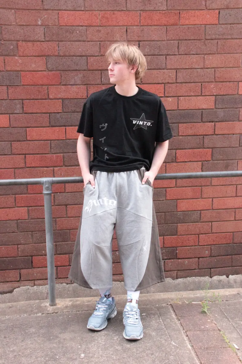 Model wearing VINTO grey jorts with a black VINTO tee against a brick wall